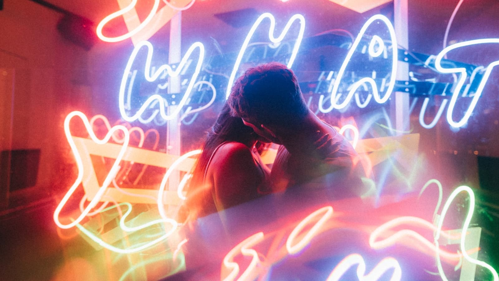 A couple close together under neon lights